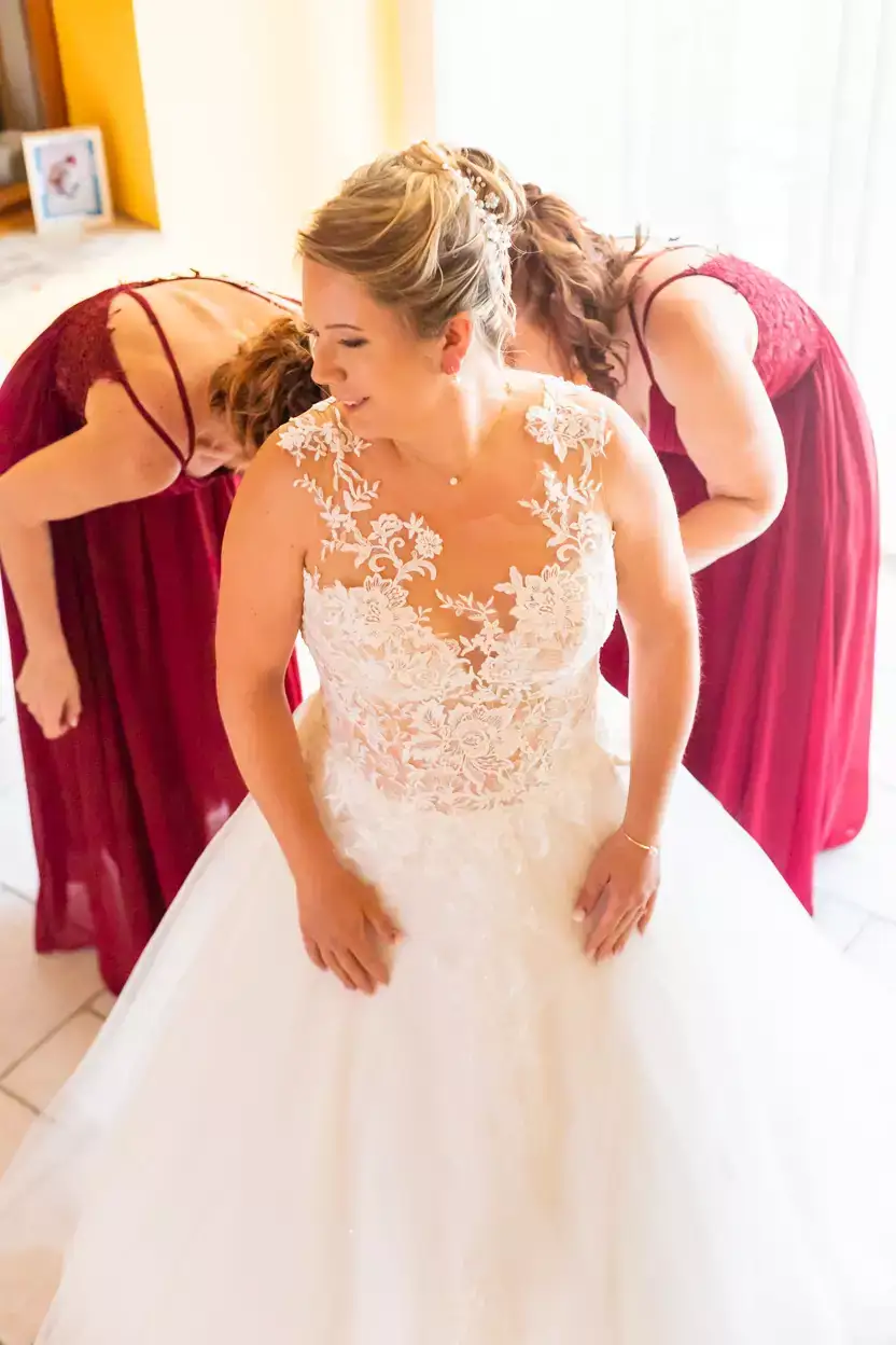 Les témoins aident la mariée à enfiler sa robe
