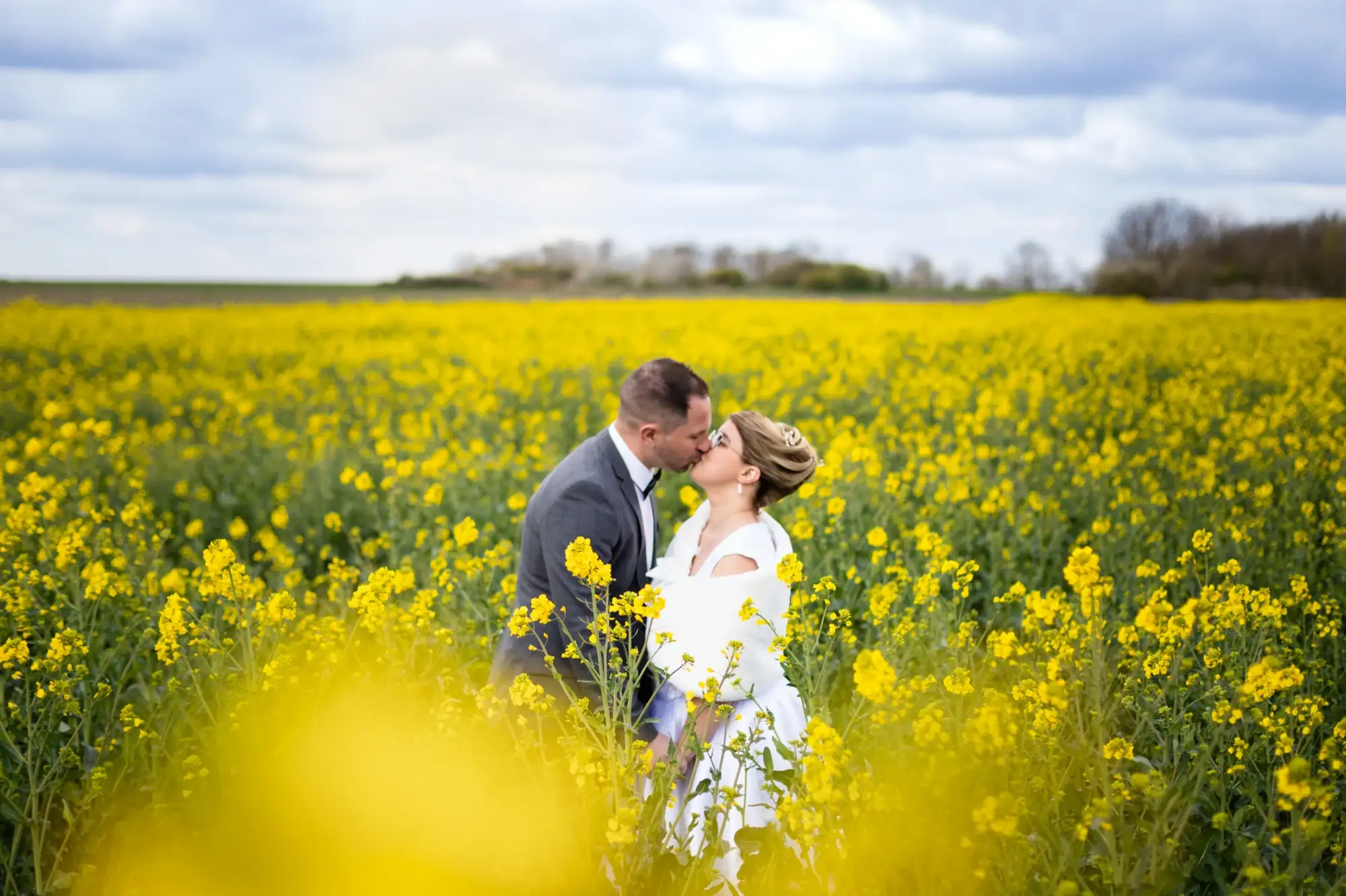 photo de couple de mariés dans un champs de colza